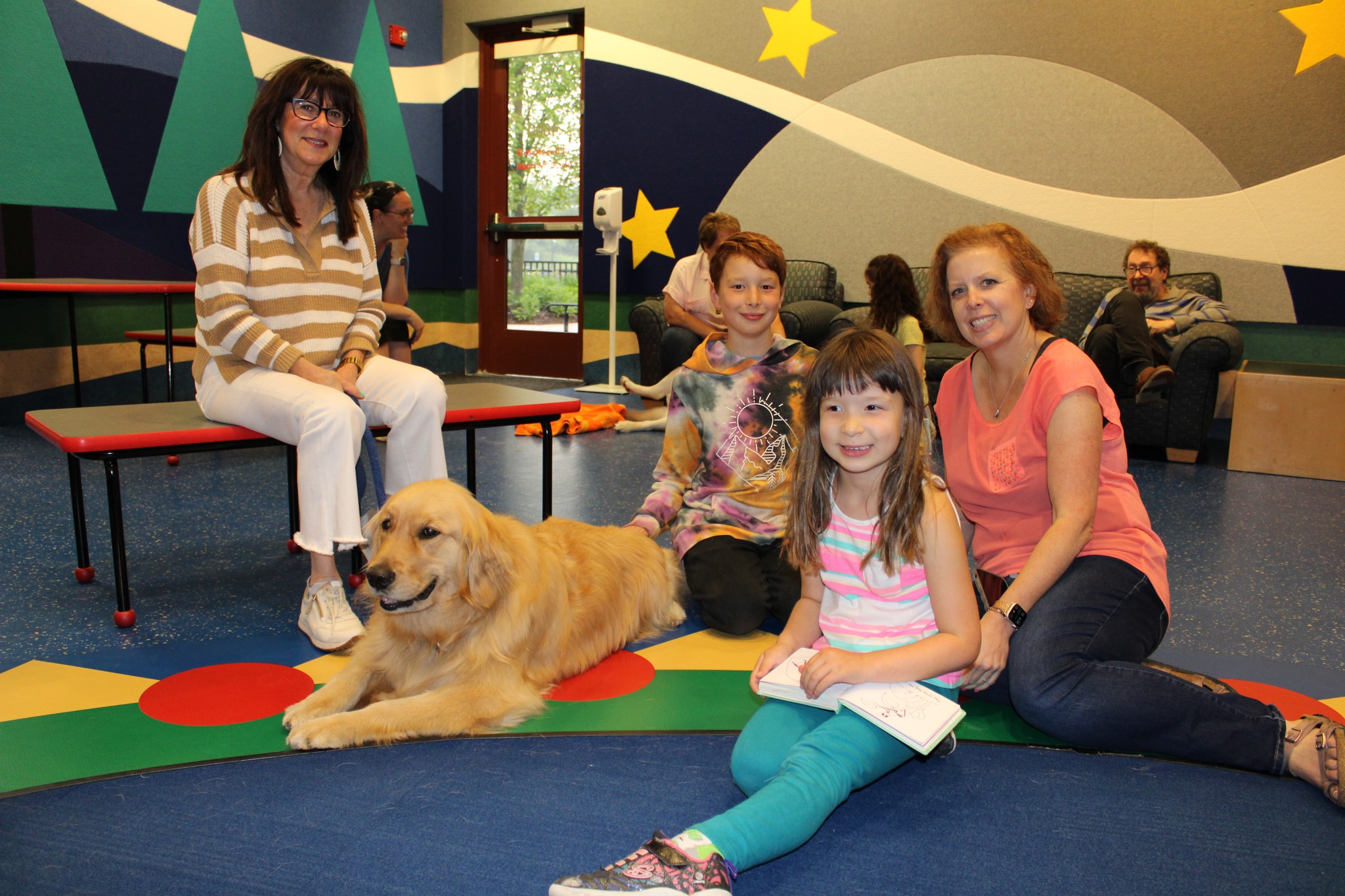 A family sits with a golden retriever at the Read to a Dog event