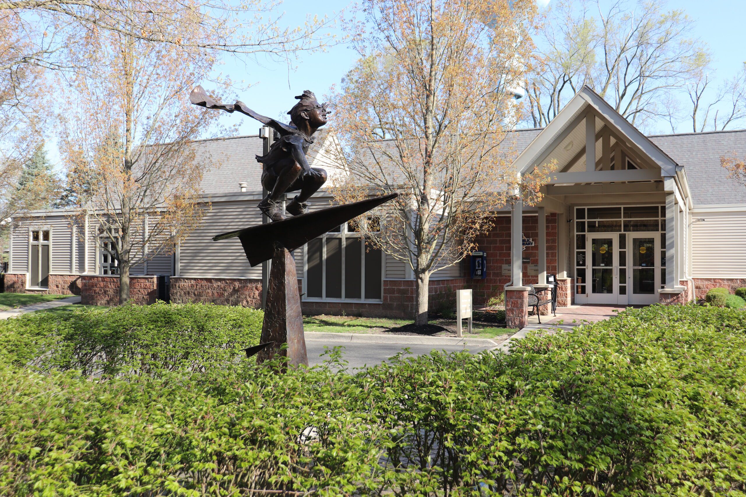 Entry of the Westacres Branch across from a bronze statue of a boy riding on a paper airplane