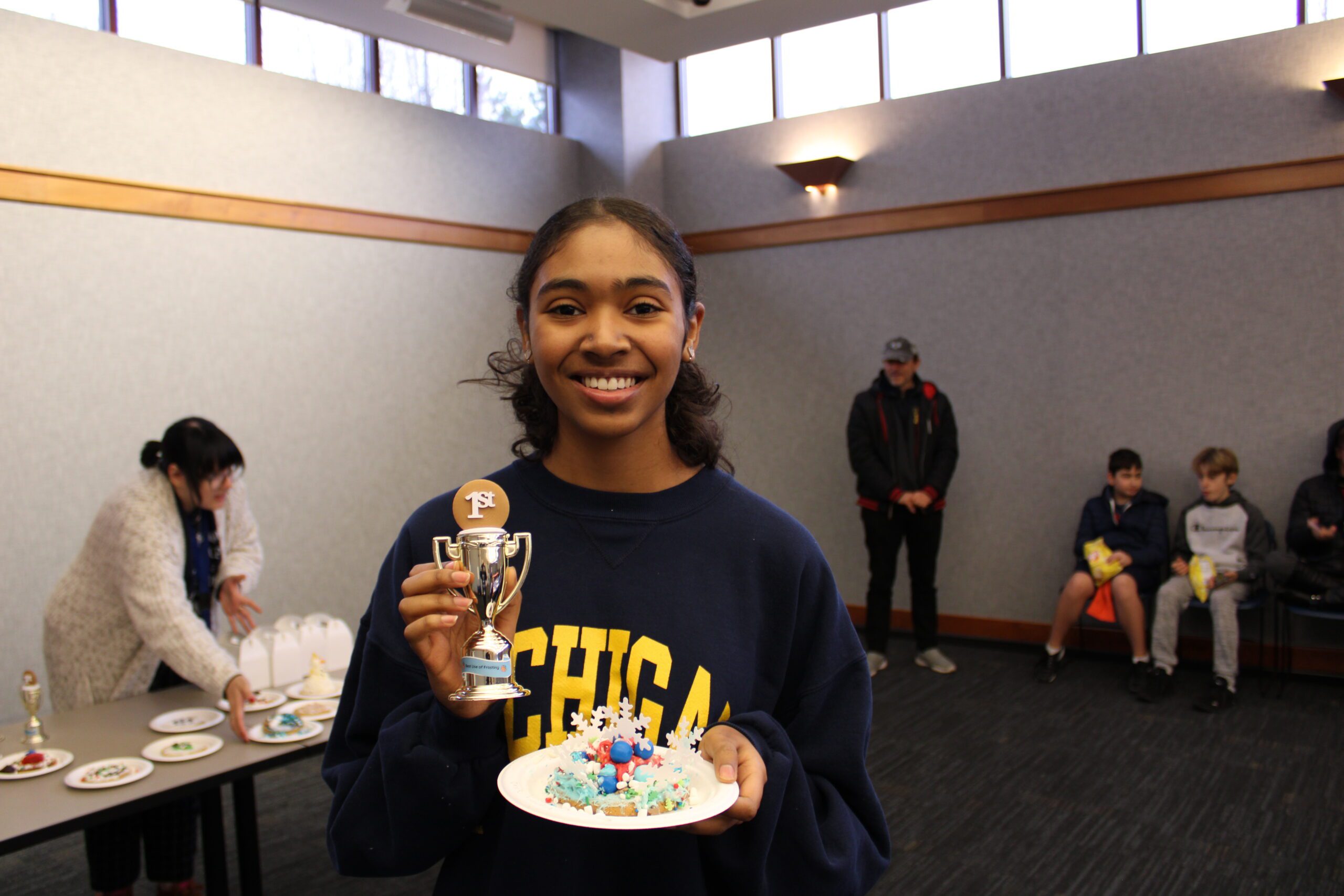 Teen holds trophy and decorated cookie in the Main Library meeting room