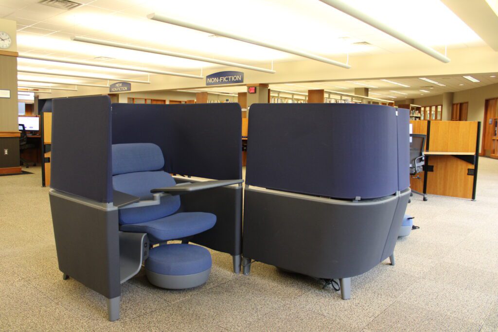 A study pod chair nestled in a private pod environment with a swivel desk, plug, and movable footstool