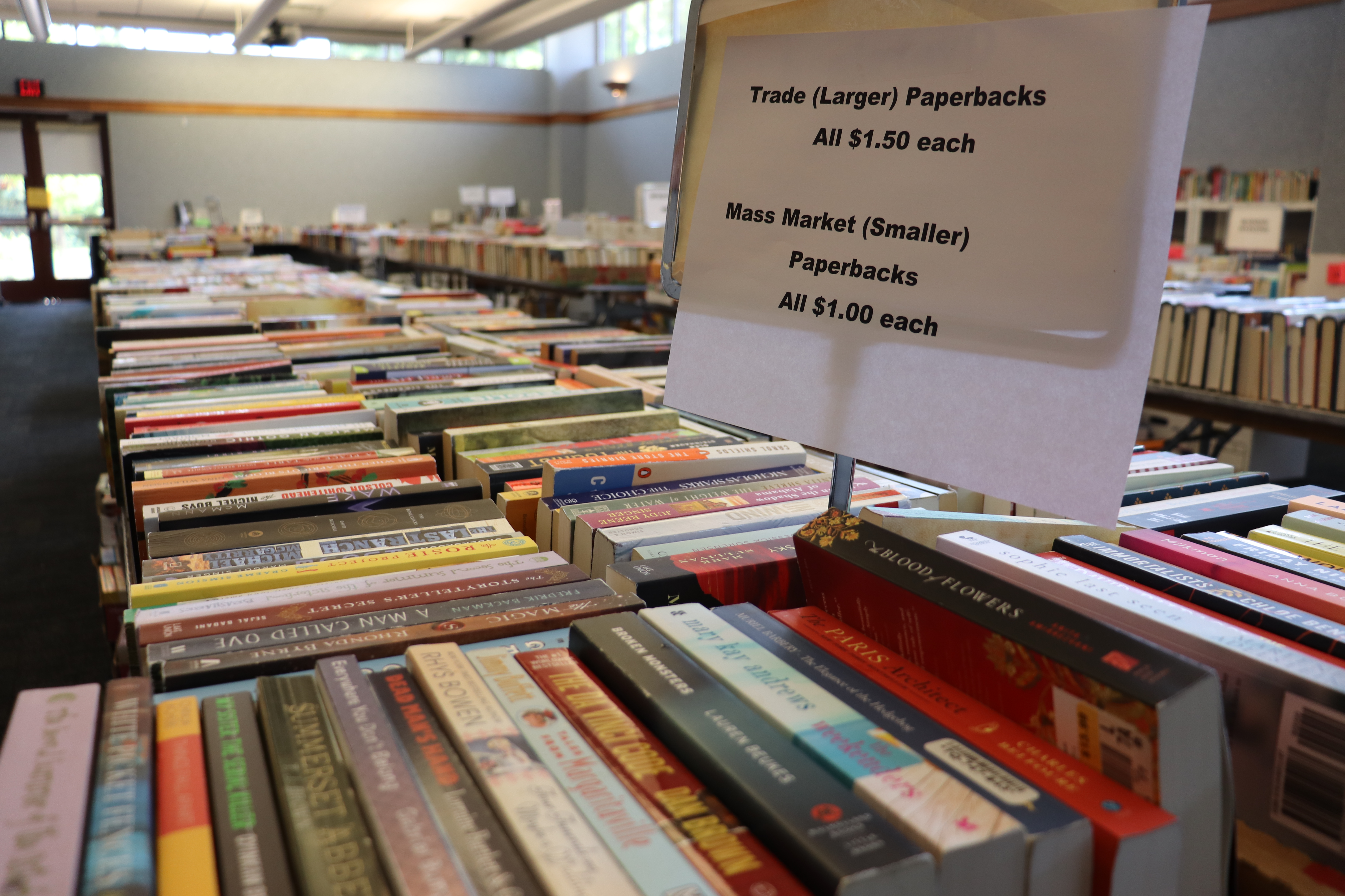 books on tables with a sign reading Trade Paperbacks - All $1.50 each | Mass Market Paperbacks - All $1 each