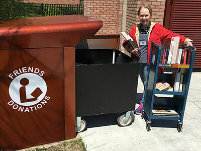 A volunteer with a cart near the Friends donations bin outside the Main Library