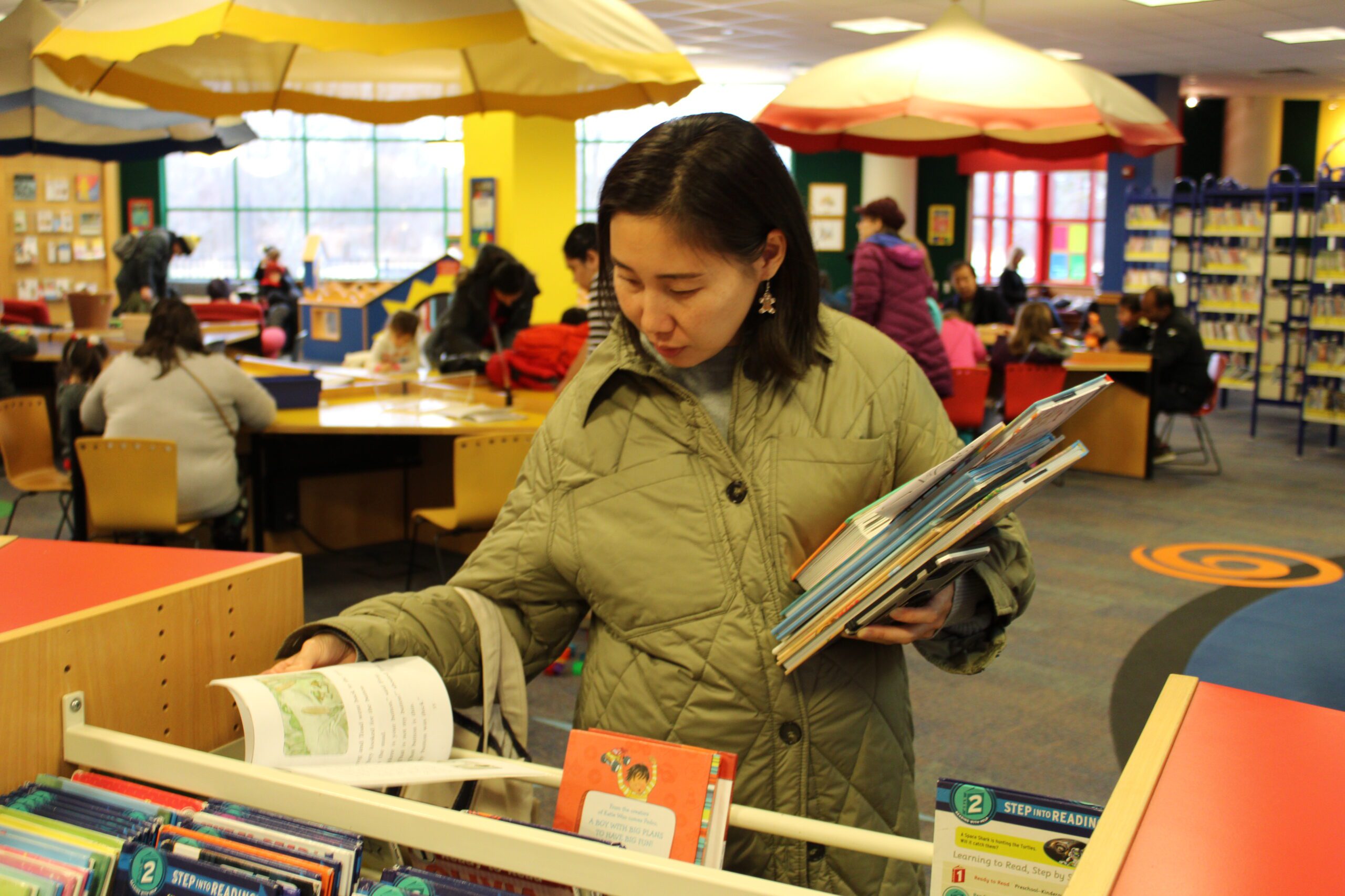 Patron looking through books in the Main Library youth area
