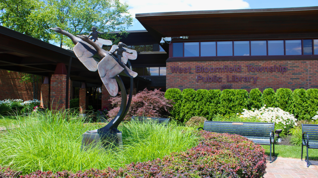 The statue in front of the Main Library in summer. The statue shows two kids, each riding a goose in flight.