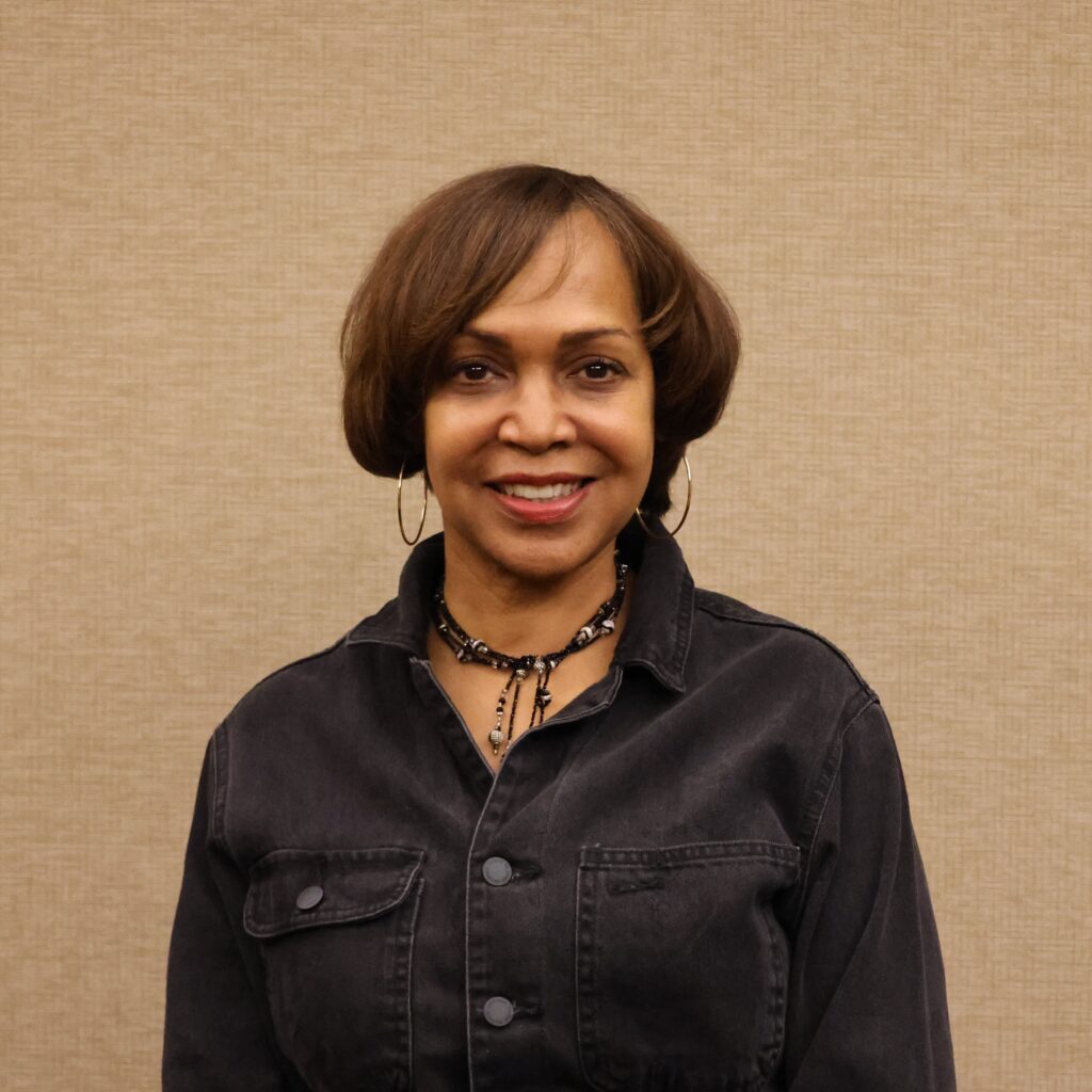 Portrait of a Black woman with short brown hair smiling at the camera