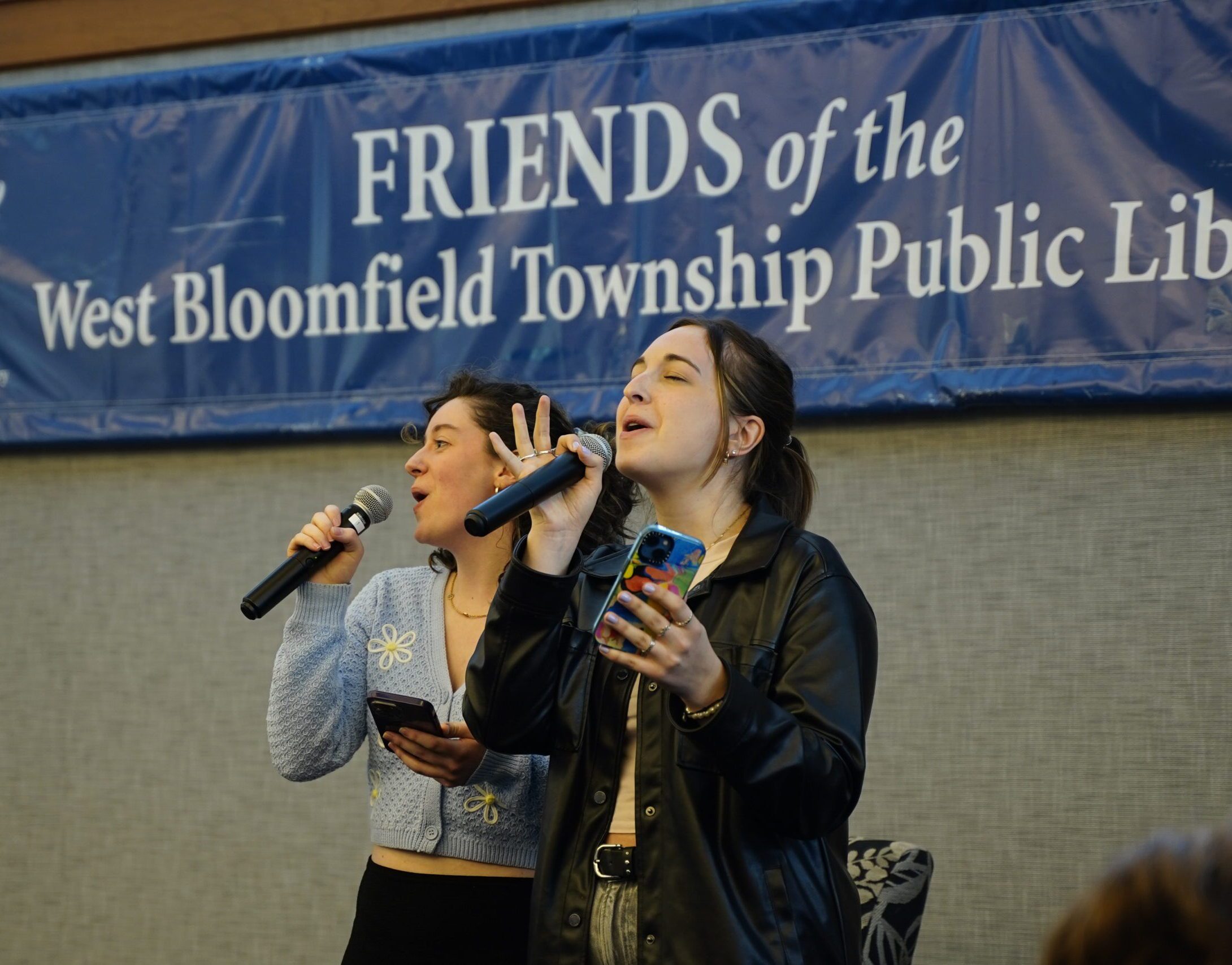 Two women sing into microphones.