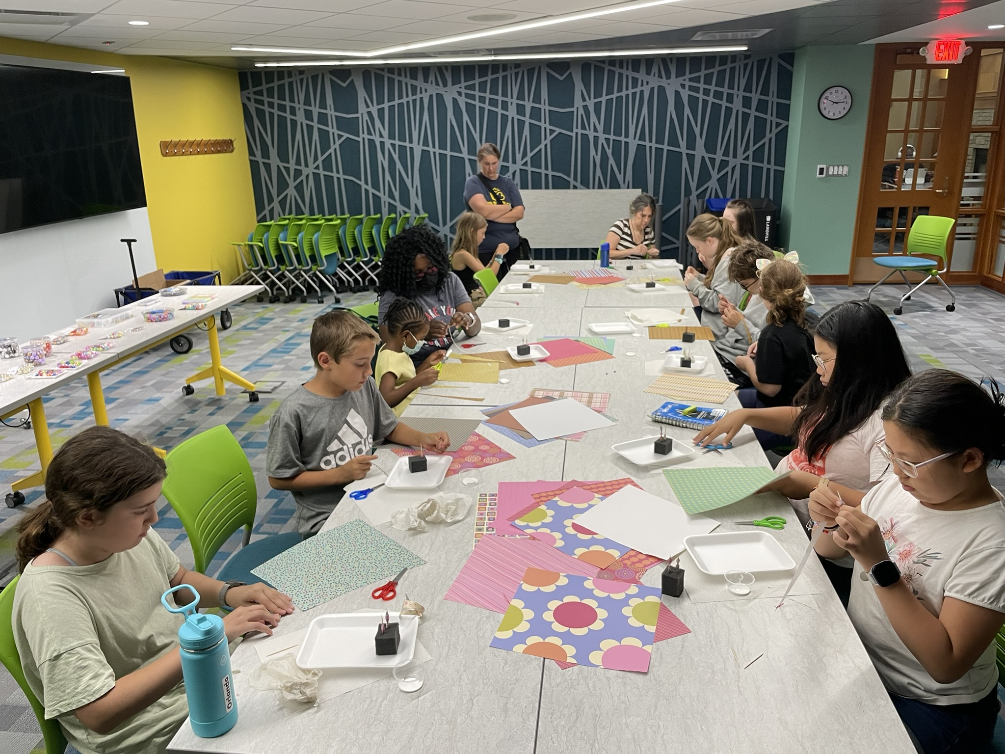 Teenagers work on a craft project at a table.