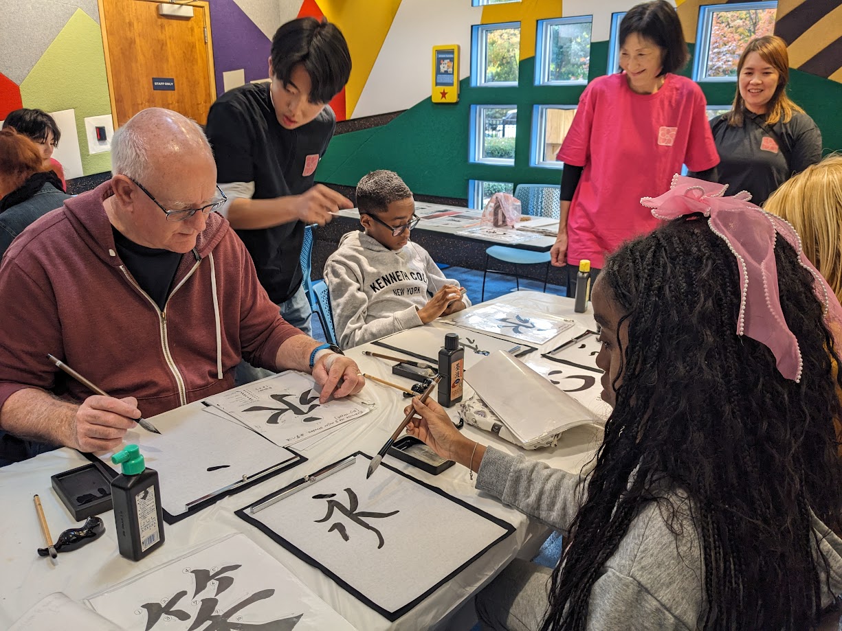 Adults and kids trying calligraphy at the Westacres Branch