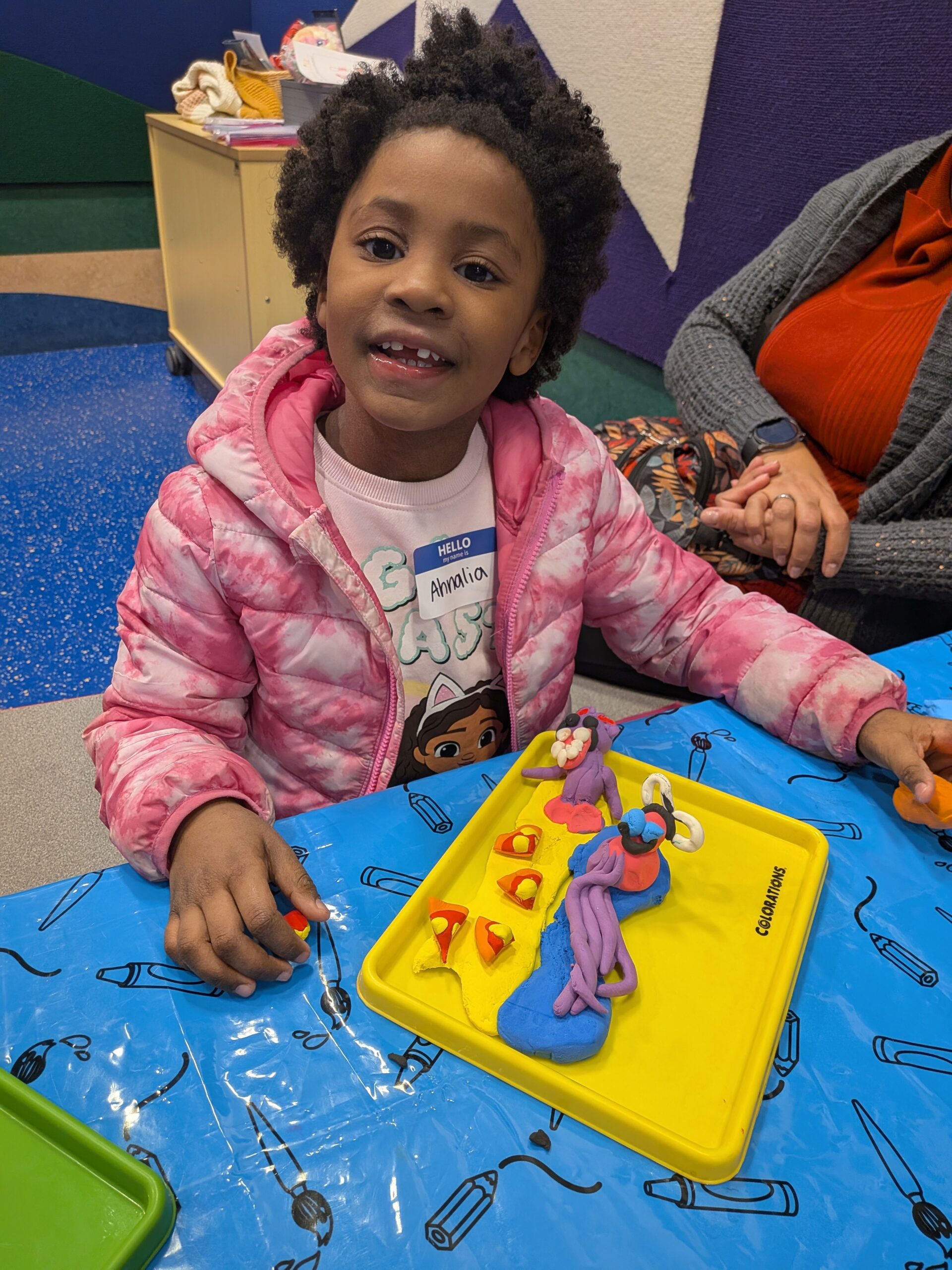 Girl smiling at the camera in front of colorful sculpture creation